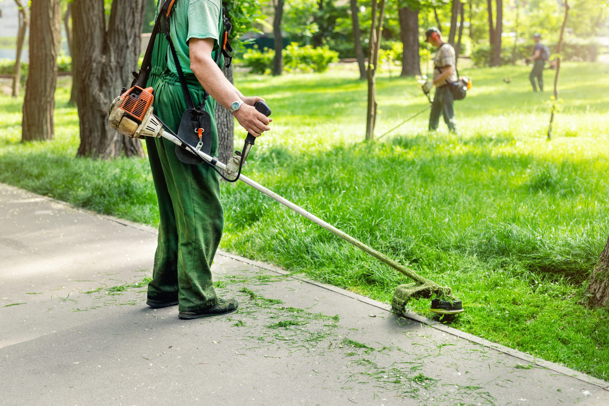 groundskeeper trimming grass at a public park