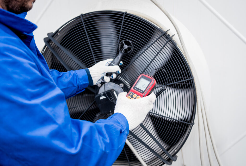 HVAC worker checks a school asset using an anemometer.